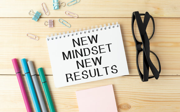 New mindset new results words letter, written on notepad, work desk top view. Motivational self development business typography quotes concept