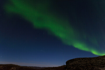 Fototapeta na wymiar Beautiful northern lights in winter over the tunra and hills.