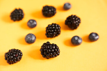 Blackberries and blueberries on an illuminating yellow background. High quality photo