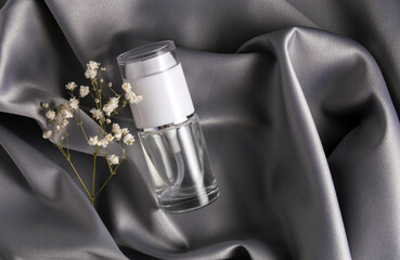 Luxury cosmetics concept. Still life on a shiny, delicate gray fabric. Beauty product with dry flower
