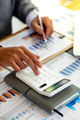 Close up Business man using calculator and laptop for do math finance on wooden desk, tax, accounting, statistics and analytical research concept