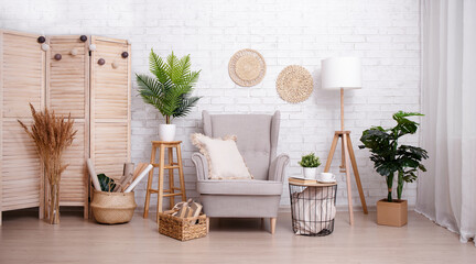 Room with armchair, lamp and plants over brick wall