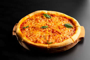 Pizza is not a wooden board. Black background. close-up.