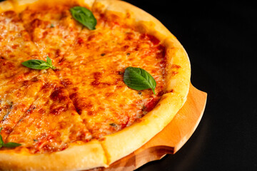 Pizza is not a wooden board. Black background. close-up.