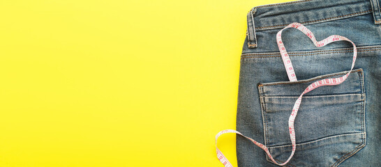 blue jeans with measure tape in pocket in form of a heart. concept of healthy lifestyle and diet with love to your body - obrazy, fototapety, plakaty