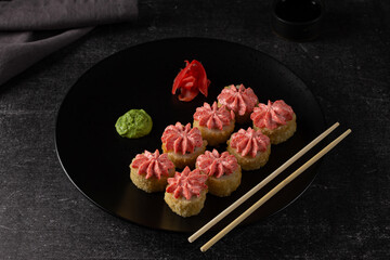 Sushi roll with salmon, smoked eel, avocado, cream cheese on a black background