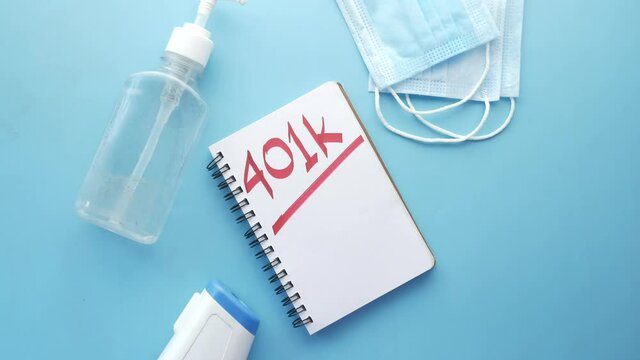 Notepad with word 401k and face mask on blue background,