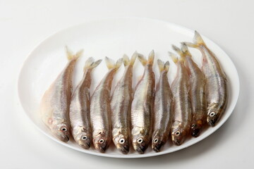 Fresh smelt fish on a white background, Small fish on a white plate. Smelt fishes (European smelt) isolated on white