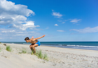 Fototapeta na wymiar Charging on the beach. A young athlete on the beach. Gymnastics classes at sea.