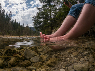 Hiker cooling feet in the cold mountain river