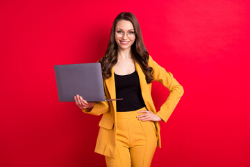 Photo of cute shiny young woman wear yellow jacket spectacles typing modern gadget smiling isolated red color background