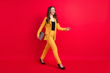 Fototapeta na wymiar Full length body size view of attractive chic slim cheerful lady walking carrying laptop isolated over vivid red color background