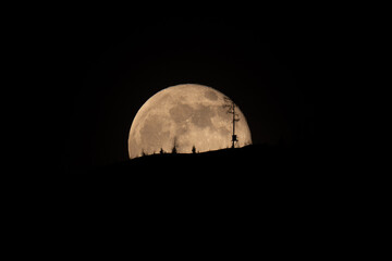 beautiful moonrise over the mountains with tree silhouettes on the horizon