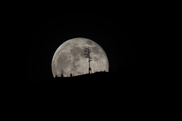 beautiful moonrise over the mountains with tree silhouettes on the horizon