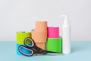 Rolls of kinesiology tape for athletes, scissors and antiseptic bottle on white background. Copy space for text