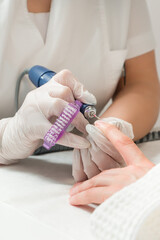Obraz premium Woman in a nail salon receiving a manicure by a beautician with nail file. Beauty and hand care close-up.