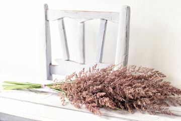 
Vintage rural still life. Rough wooden chair and a bouquet of dry pink grass