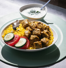 Garnished chicken Madras with Pulao rice in a white bowl