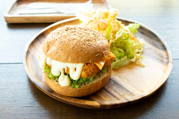 Fried fish fillet burger with vegetable salad on wood plate background