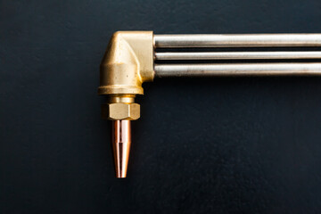 Gas cutter on a black background. New bronze torch with copper tip.