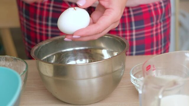 Women's hands separate the yolk from the white in a broken egg. Cooking Belgian Waffle Dough