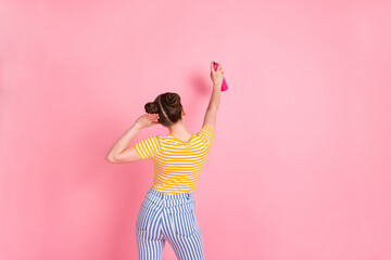 Photo of young pretty lovely funky funny careless girl painting walls with sprayer isolated on pink color background