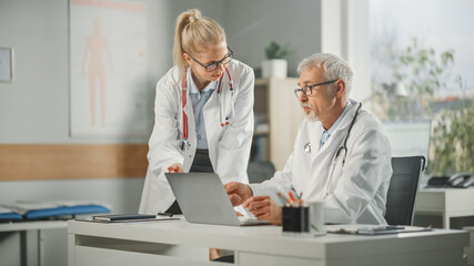 Doctor's Office: Physician Talks With Professional Head Nurse, Using Desktop Computer. Medical...