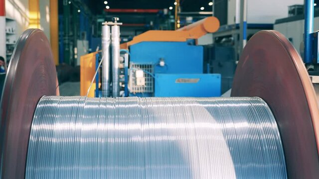 Thick silver cable unwinding from a big metal spool