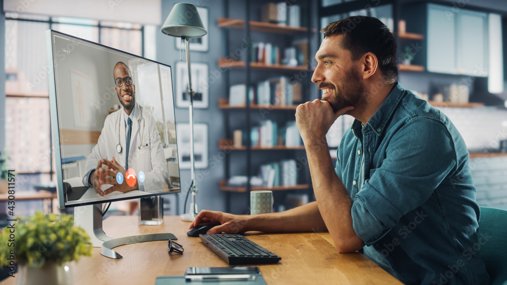 Poster handsome caucasian male is making a video call to his medical consultant on desktop computer at home
