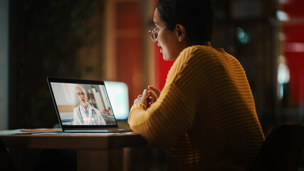 Beautiful Multiethnic Latin Female is Making a Video Call to a Doctor on Laptop Computer in...