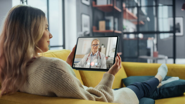 Close Up of a Female Chatting in a Video Call with Her Female Family Doctor on Digital Tablet from Living Room. Ill-Feeling Woman Making a Call from Home with Physician Over the Internet.