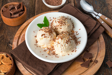 Summer refreshing dessert on a brown background. Ice cream with chocolate and cookie crumbs.
