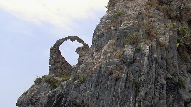 Ruins of an ancient watchtower on the edge of a sheer cliff face along the Palinuro coastline, Salerno, Italy.
