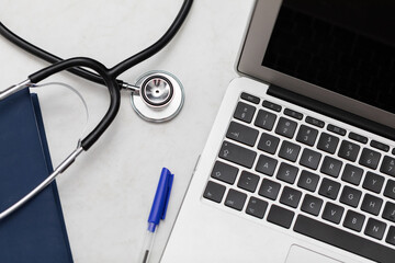 The stethoscope sits on the desk and next to it is a laptop and a book calendar.