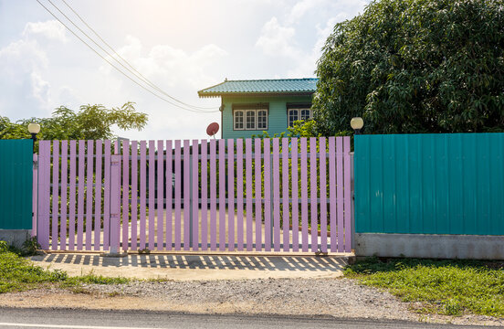 A large pink fence gate close to the house.