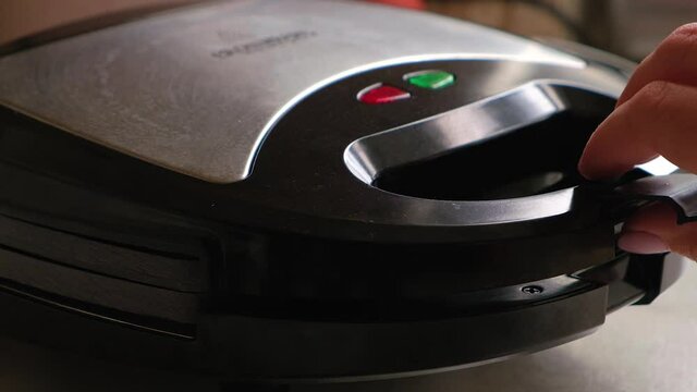Liquid dough poured waffle iron machine to prepare sweat Belgian waffle dessert. Close up shot.