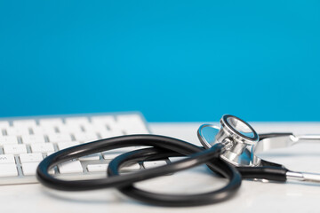 Close-up view of a stethoscope lying on a desk next to a computer keyboard. Close-up view.