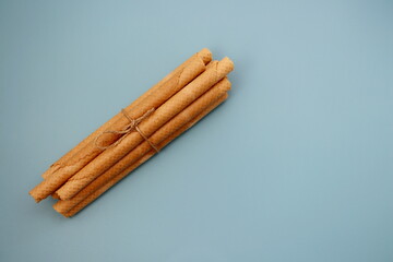A bunch of wafer rolls on a blue background. Long wafer rolls