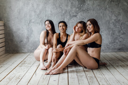 friendship, beauty, body positive and people concept - group of happy women different in underwear over gray background