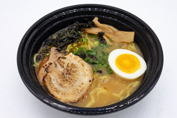Black Bowl of Shoyu Ramen filled with Pork and an Egg on a White Background