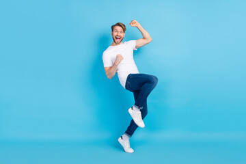 Fototapeta na wymiar Full size profile photo of impressed positive man fist knee up open mouth isolated on blue color background