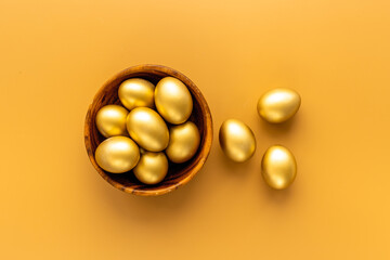 Golden Easter eggs in wooden bowl. Wealth and good luck concept.