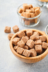 Cane sugar cube in bamboo bowl on gray table concrete background. Top view.