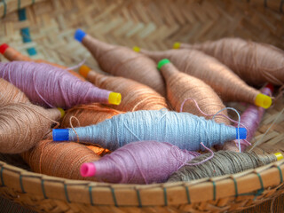 Close up many color cotton thread bundle on rattan basket.  Weaving is old Thai traditional culture...