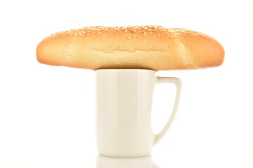 One fresh flavored bagel with a white ceramic cup, close-up, isolated on white.
