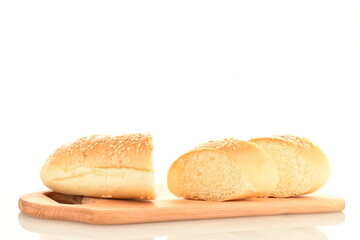 One fragrant bagel cut into slices sprinkled with sesame seeds on a wooden board, close-up, isolated on white.