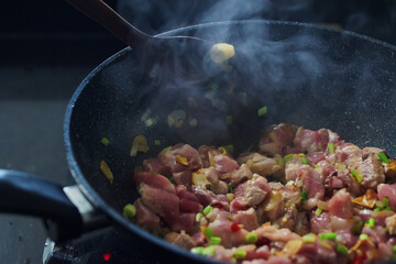 Close-up view of the raw pork in the pan during cooking