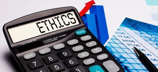 On the calculator display there is an inscription ETHICS. Nearby are colored diagrams and graphs. Business concept