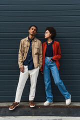 Fototapeta premium full length of young african american man posing with stylish woman standing with hand in pocket