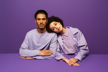 Obraz premium young african american woman leaning on man isolated on purple